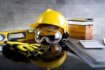 Contractor theme. Tool kit of the contractor: yellow hardhat, libella and tools on the gray tiles background.