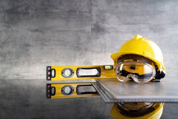 Contractor theme. Tool kit of the contractor: yellow hardhat, libella and tools on the gray tiles...