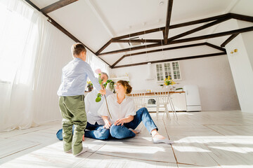 Fototapeta premium Little boy gives a rose to young parents