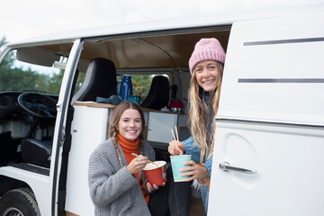 Portrait happy young women friends eating instant noodles in van