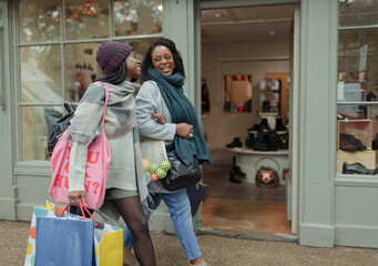 Happy mother and daughter with shopping bags walking arm in arm