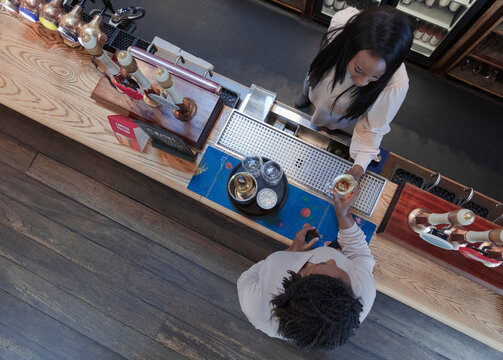 Bartender serving wine to woman at bar counter