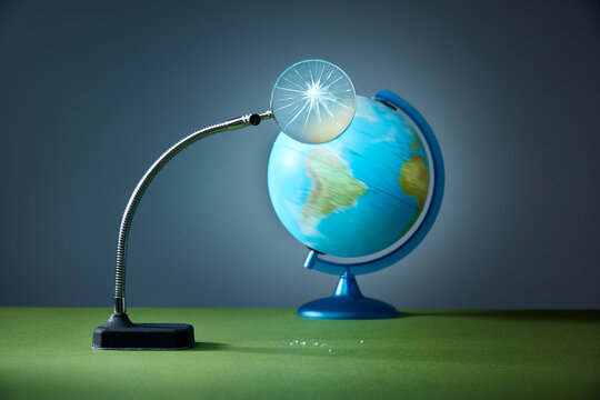 Broken magnifying glass over spinning globe
