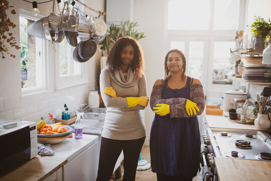 Portrait confident mother and daughter cleaning kitchen
