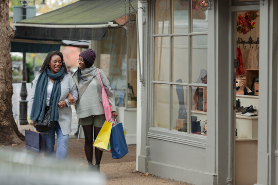 Happy mother and daughter walking arm in arm with shopping bags