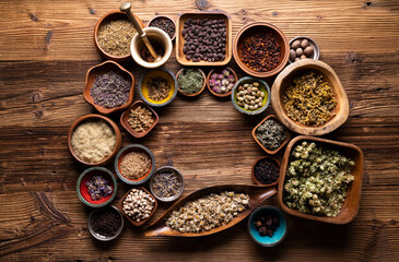 Fototapeta na wymiar Natural medicine background. Assorted dry herbs in bowls and brass mortar on rustic wooden table.