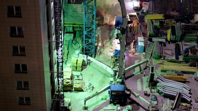 Construction workers pouring wet concrete using concrete spider hose or pump work at high-rise site in night