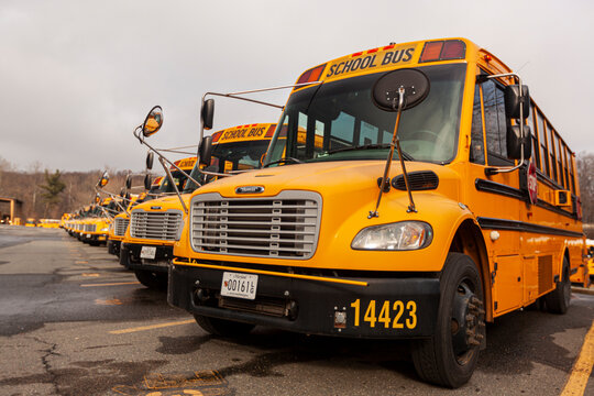 Bethesda, MD, USA 12-21-2020: Close up selective focus frontal view of a school bus fleet at a parking lot. These are yellow Thomas Saf-T-Liner C2 vehicles with stop sign and crossing arms attached.