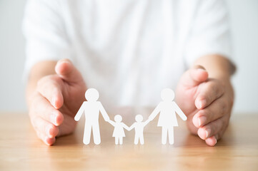 Fototapeta na wymiar Hand protecting family on wood table. Healthcare and life insurance concept