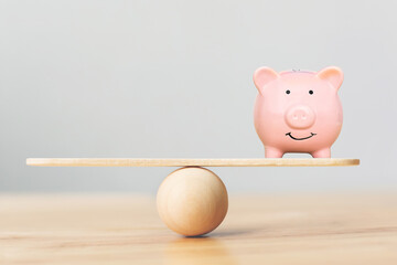 Piggy bank on wood scale seesaw and copy space. Save money and investment