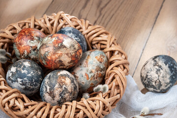 Easter composition - Easter eggs painted with natural dyes in a wicker nest on a wooden table