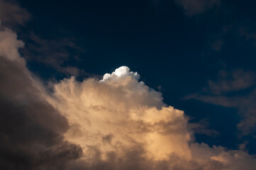 Obraz premium Cumulunimbus clouds with a dense formation illuminated by a sunlight.