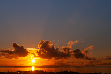 Fototapeta na wymiar Vibrant sunrise rising behind Ishigaki island with colorful clouds seeing from Iriomote Island.