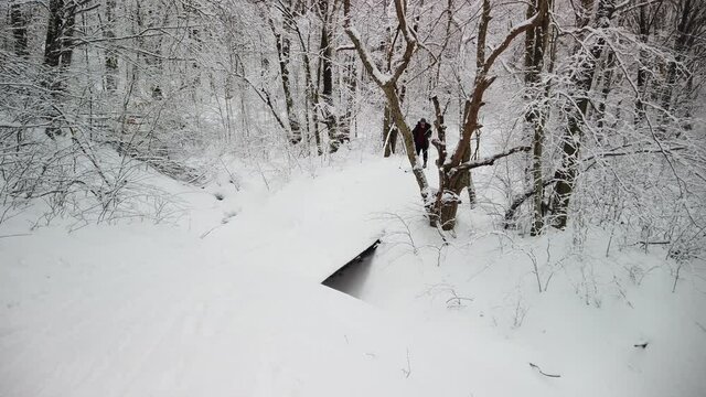 Teen boy skiing across a snow covered bridge smiling and laughing in slow motion.