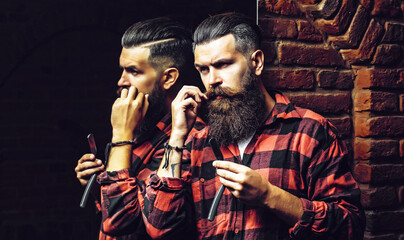 Bearded man with razor near mirror. Man with long beard. Handsome man hipster or guy with beard and...