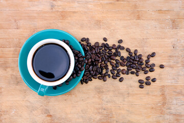 A cup of black coffee and scattered beans
