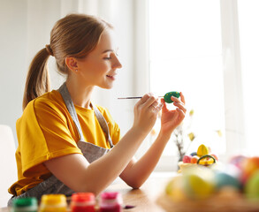 Cheerful woman painting Easter eggs at home