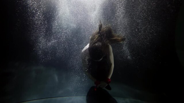 mystery underwater shot with floating female figure, slow motion in depth, swimming pool