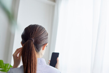 リビングでスマートフォンを操作する若い女性