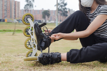 Obraz premium girl putting on the roller skates tying the shoelaces and wearing a mask