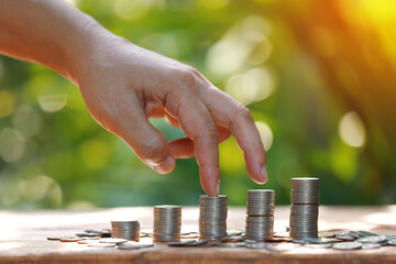 Coins a men's hand  placed and sorted coins on a wooden board.