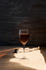 Glass of red wine in arched sunlight on the sand.