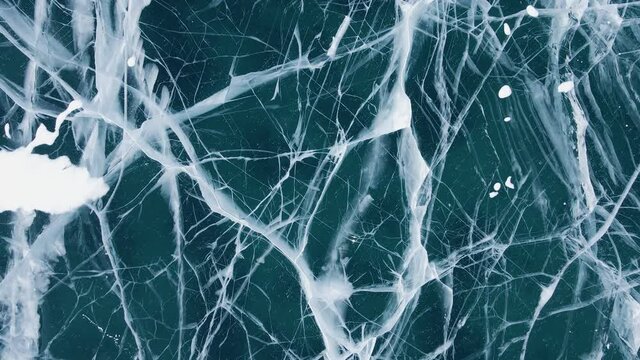 Frozen Lake Baikal, Aerial view. Beautiful winter landscape with clear smooth ice. Famous natural landmark Russia. Blue transparent ice with deep cracks, top view of a frozen lake.