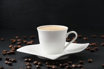 White cup of coffee on a black background. Close-up side view. Coffee beans on a black table.