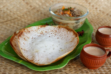 Appam, Hoppers and mutton stew Kerala breakfast food and Indian milk tea chai, christian breakfast India Sri Lanka Tamil Nadu fermented rice pan cake. Indian veg food.
