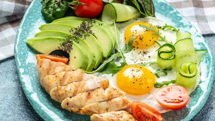 Healthy breakfast, ketogenic. Chicken grilled fillet with salad fresh tomatoes, cucumbers, eggs and avocado. Food recipe background. Close up