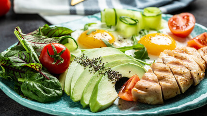 Healthy breakfast, ketogenic. Chicken grilled fillet with salad fresh tomatoes, cucumbers, eggs and avocado. Food recipe background. Close up
