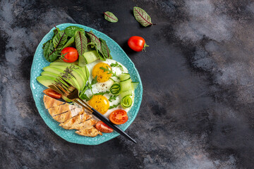 Ketogenic breakfast. Keto low carb chicken grilled fillet with salad fresh tomatoes, cucumbers, eggs and avocado. Keto Paleo diet menu. top view