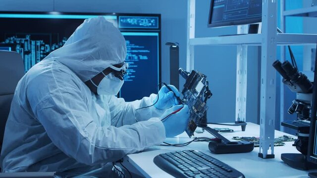 African-american microelectronics engineer works in a modern scientific laboratory on computing systems and microprocessors. Electronic factory worker is testing the motherboard and coding.