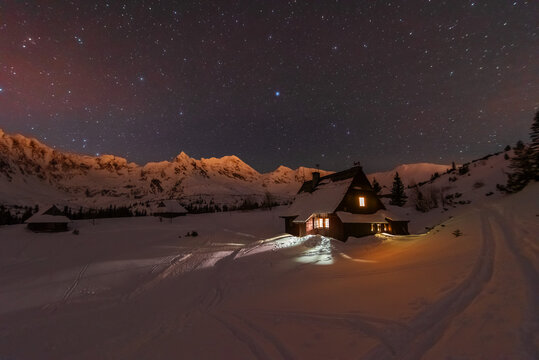 Night winter landscapes in the High Tatras, with mountain houses on a background of snow-capped mountains and starry sky