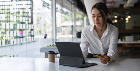 Fototapeta premium Young woman holding credit card and online shopping or online payment transaction on computer tablet.