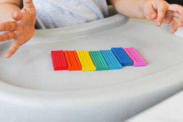 Child sculpts a figure of a flower of seven colors of colored clay. Home education of the child at...