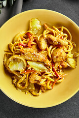 Curry Udon Noodles. Asian curry udon in yellow plate with wooden chopstick on dark slate table....