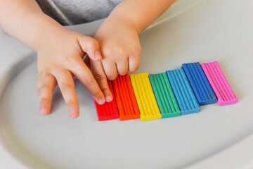 Child sculpts a figure of a flower of seven colors of colored clay. Home education of the child at...