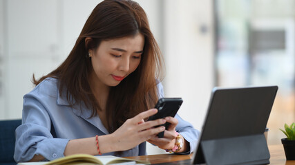Young woman working with computer tablet and using mobile phone at office.