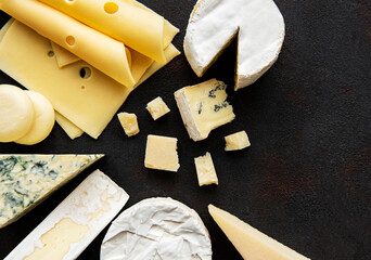 Various types of cheese  on a black concrete background