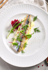 Herring Fish and Mashed Potatoes Plate. Garnished with green onion and beet salad. White restaurant plate on grey table. Salad, Healthy, Appetizer rustic food concept.
