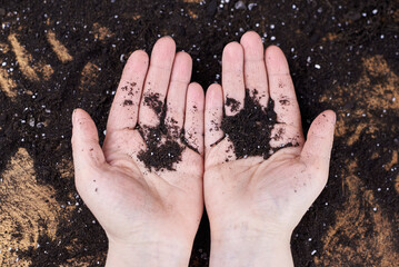 The hands of a woman farmer are holding a handful of earth.