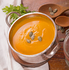 Bowl of pumpkin soup on rustic wooden background