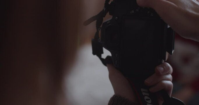 Extra close up photographers hands focusing making portrait of boy by Christmas tree. Faceless woman shooting kid child on professional camera slow motion. Macro view finder screen. Festive memories 