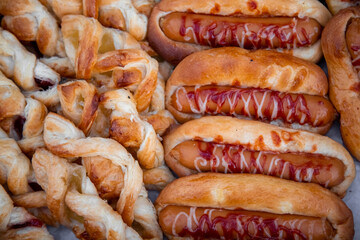 fresh delicious pastries and hot dogs on baking parchment top view
