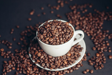 coffee beans In a saucer and in a cup of coffee on a gray background female hand macro photography