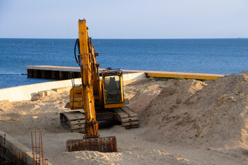 Excavator at sea straightens the sand for the beach.