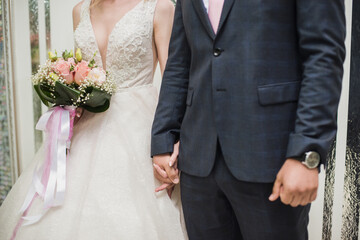 Obraz na płótnie Canvas the bride and groom hold hands
