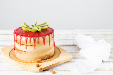 Gluten-free cake with strawberry frosting, coconut chips and almonds on a wooden stand, close-up. Copy space.
