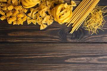 Various mix of pasta on dark wooden background. Italian food. Copy space